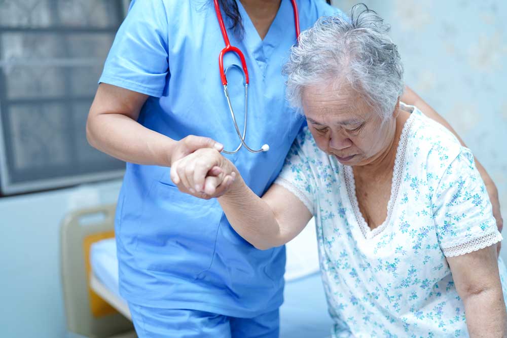 elderly female patient assisted by a healthcare worker