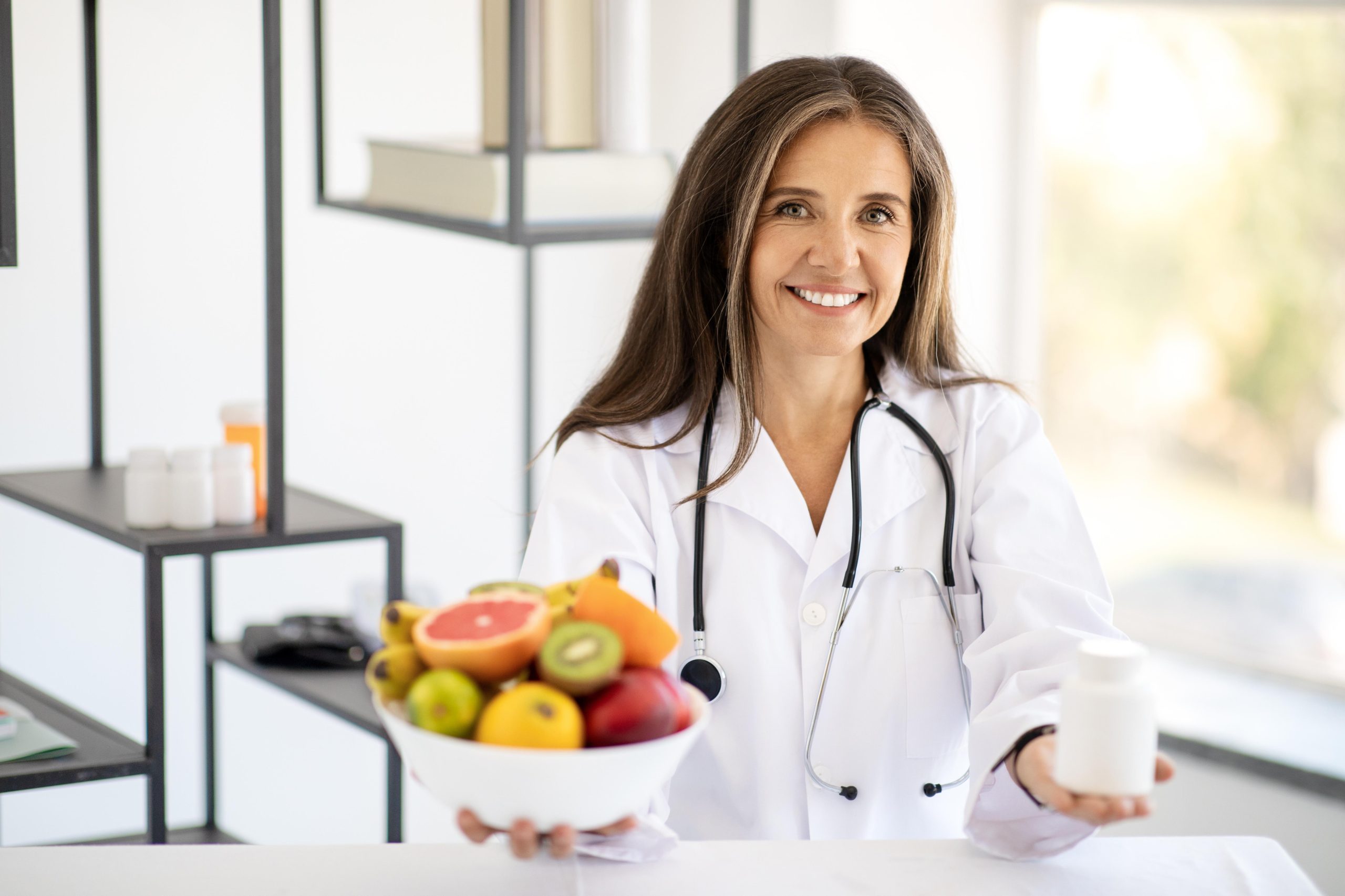 female healthcare worker holding a bowl of fruits and smiling