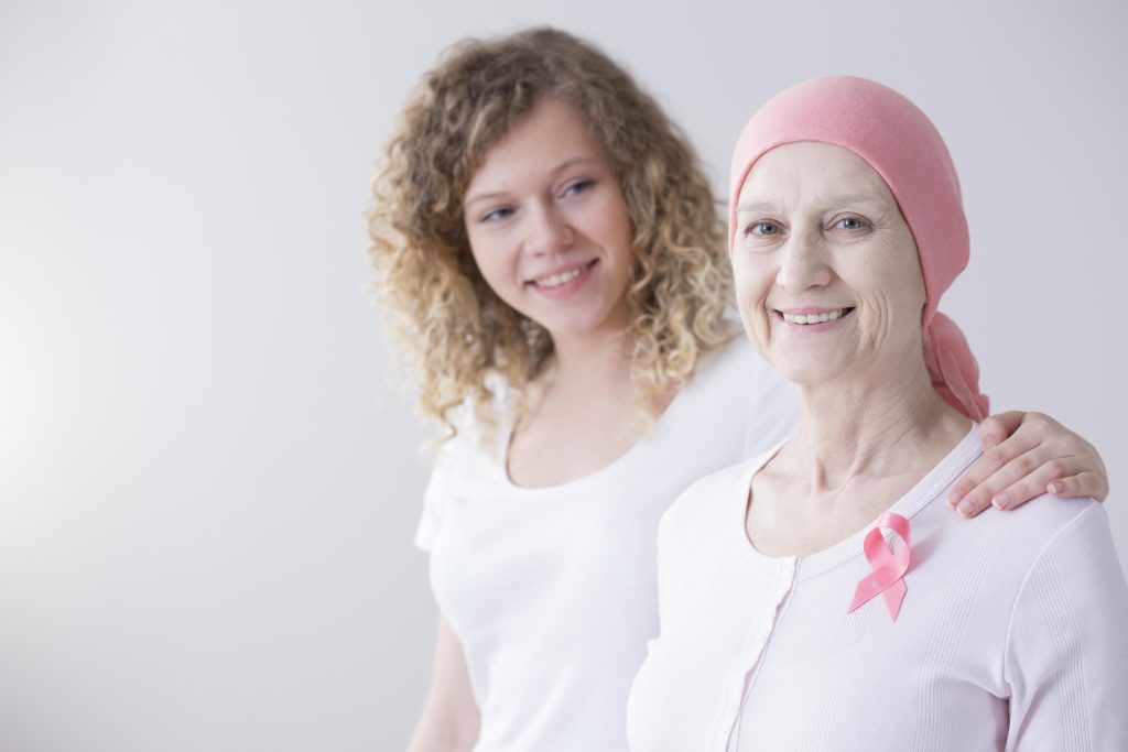 young woman with her hands on the shoulder of an elderly cancer patient